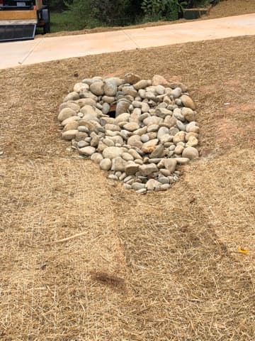 River-rock drainage feature set into a freshly seeded lawn