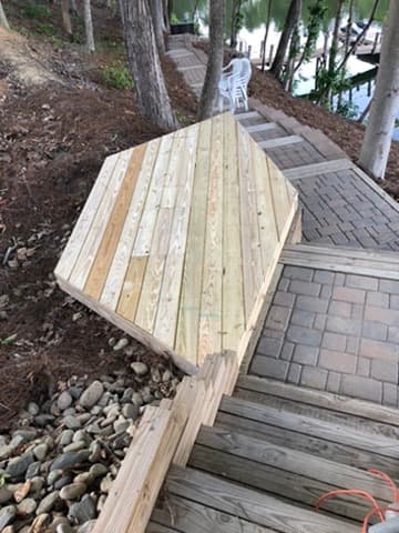 Custom-built wooden walkway leading down to the water alongside a paver path